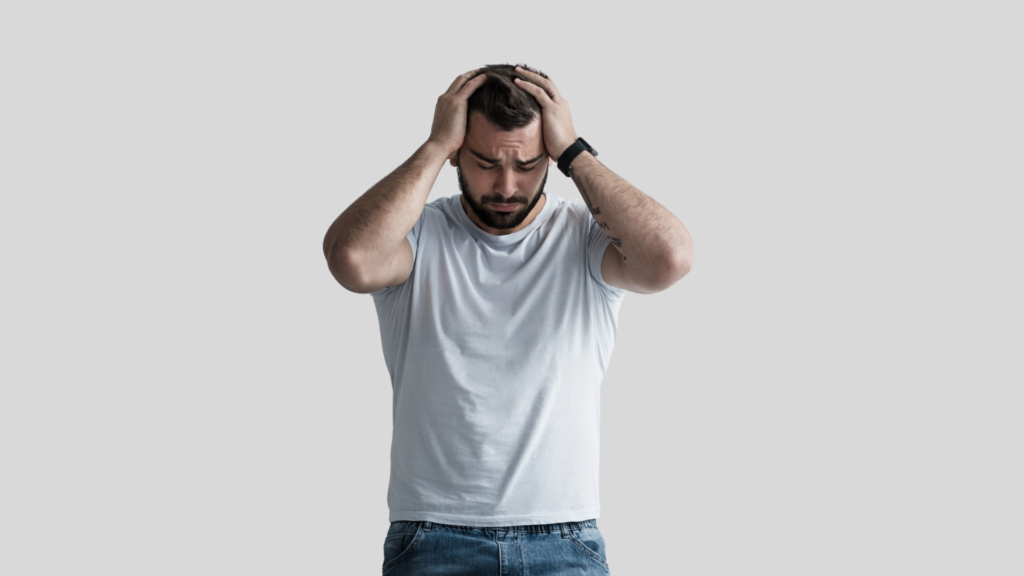 Man standing with hands on his head, showing stress and frustration, used to illustrate common mistakes men make while managing spermatorrhea and sexual health concerns
